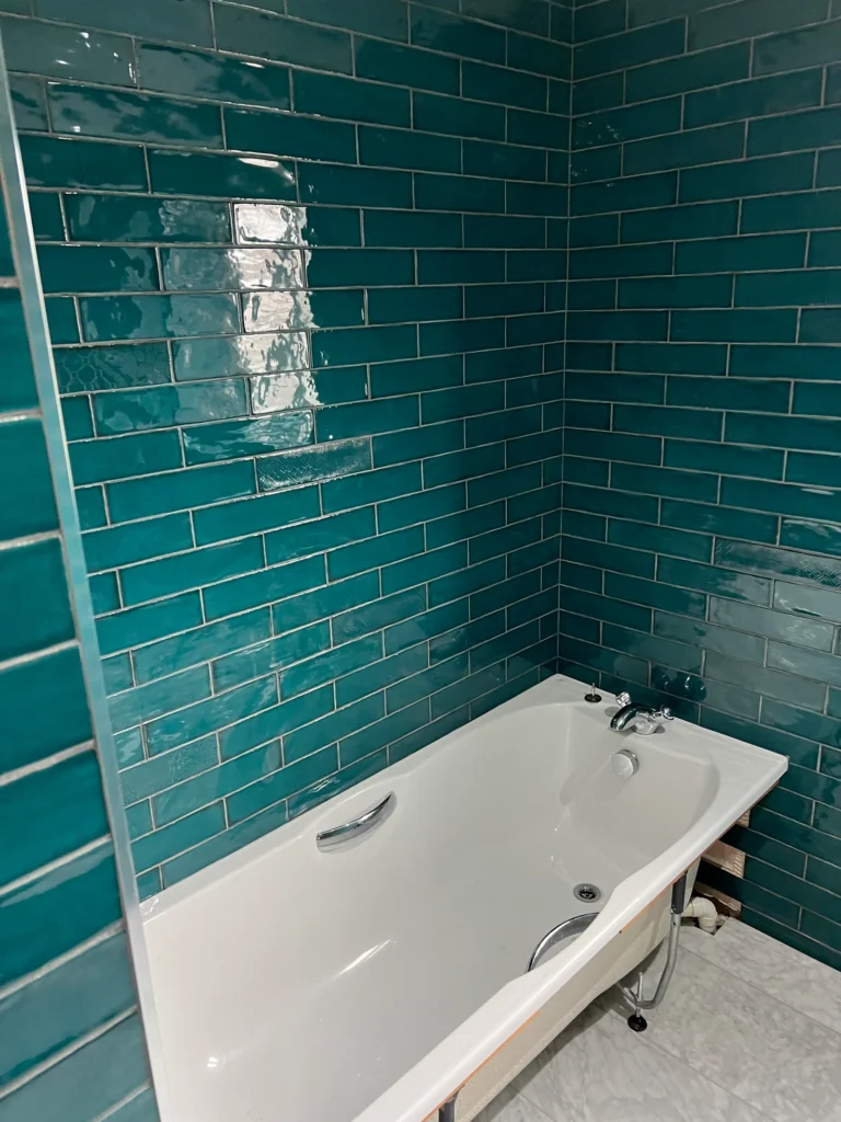 Green brick style bathroom wall tiles installed around a bath by Stamford tiler covering Stamford, Oakham and Uppingham.