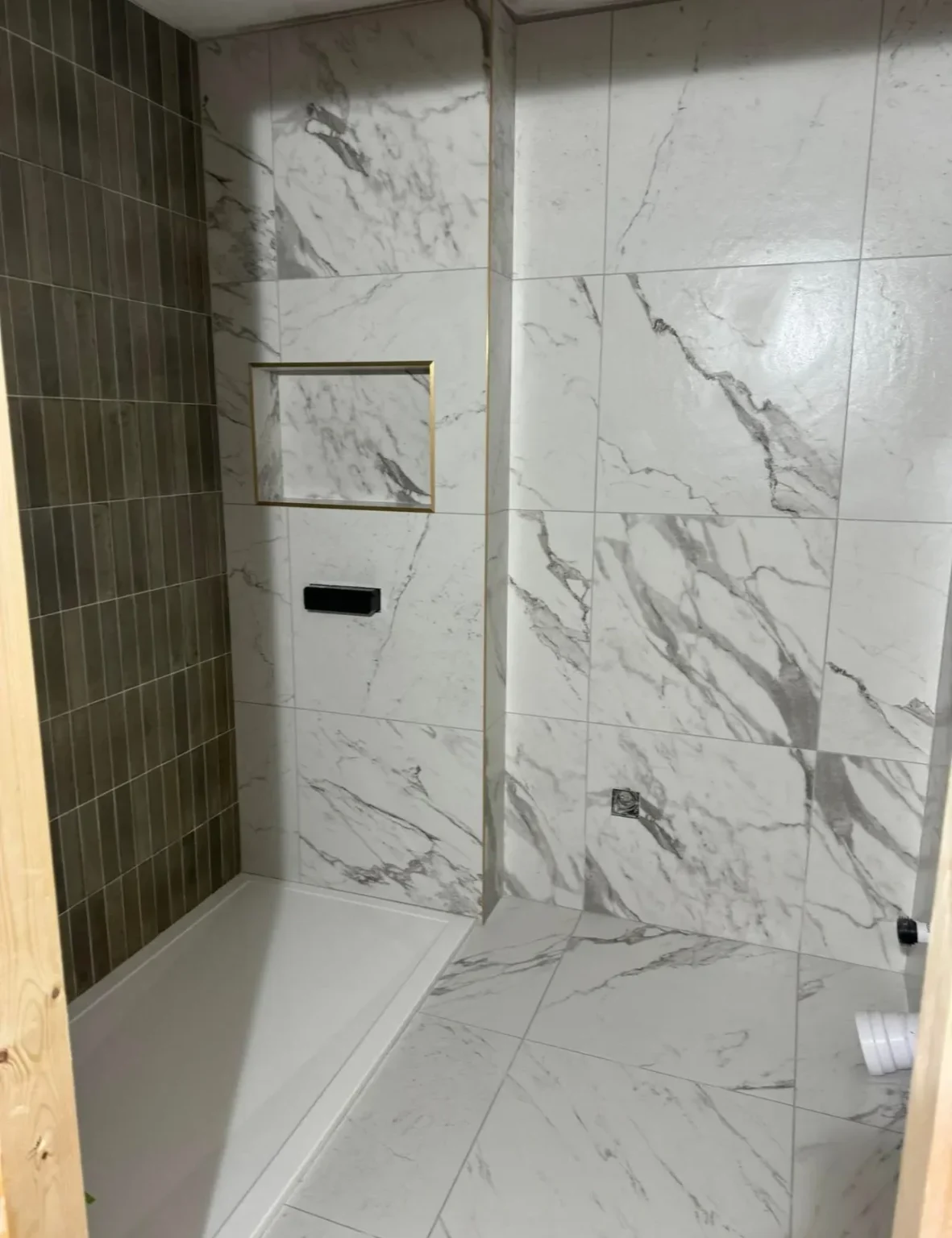 Marble effect porcelain tiles in walk-in shower with recessed shelf installed by Stamford tiler.
