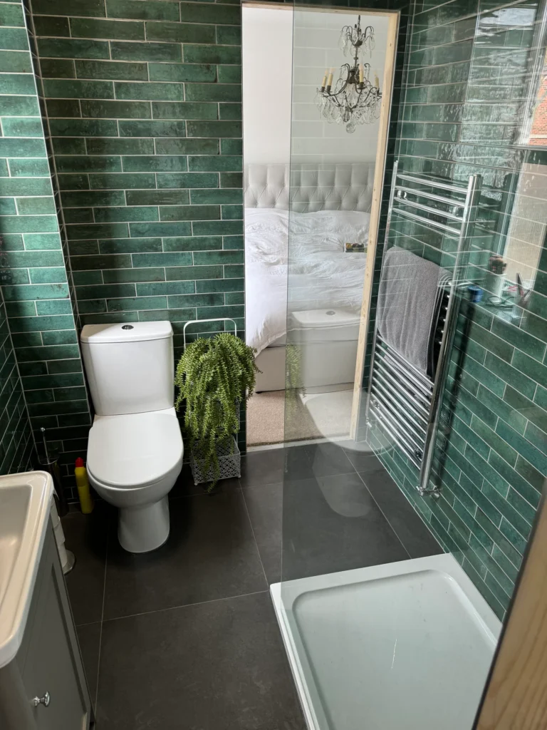 Green brick style bathroom wall tiles and dark floor tiles installed by Stamford tiler covering Stamford, Oakham and Uppingham.
