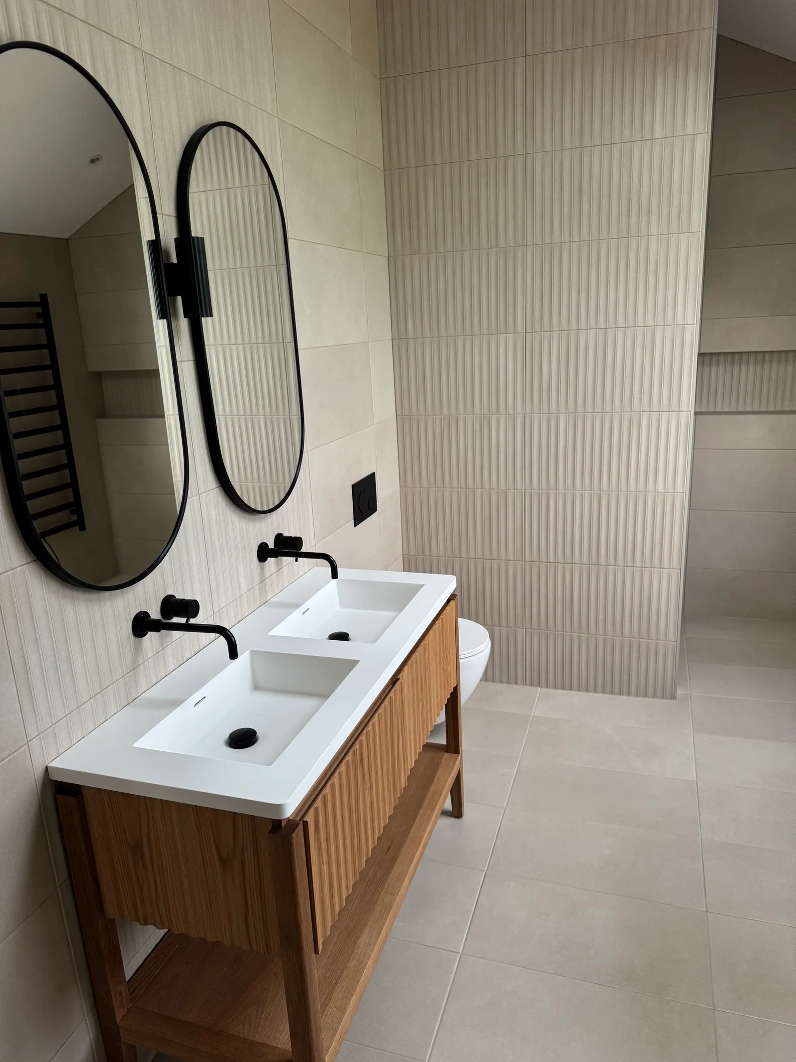 Modern bathroom tiling with textured feature wall tiles and large format floor tiles installed by Stamford tiler serving Stamford, Oakham and Uppingham.