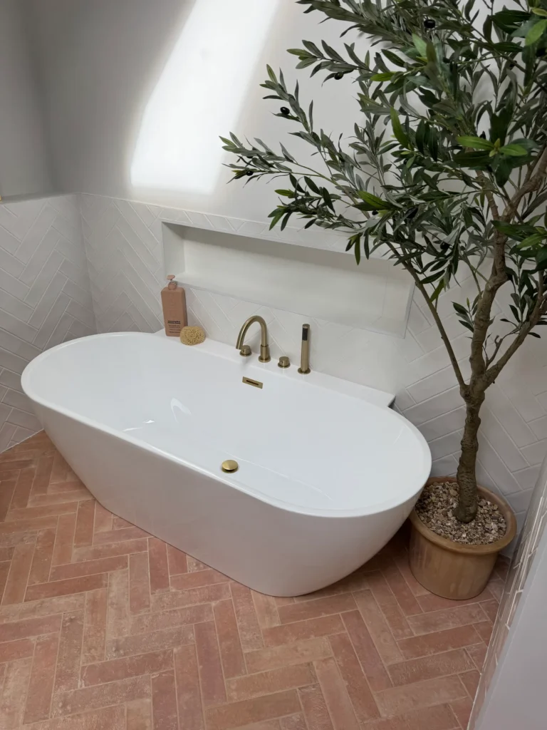 Terracotta herringbone bathroom floor tiles with freestanding bath installed by Stamford tiler covering Stamford, Oakham and Uppingham.