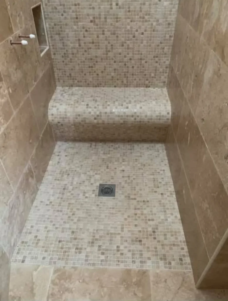 Wet room shower with mosaic tiles and tiled bench seat installed by Stamford tiler.