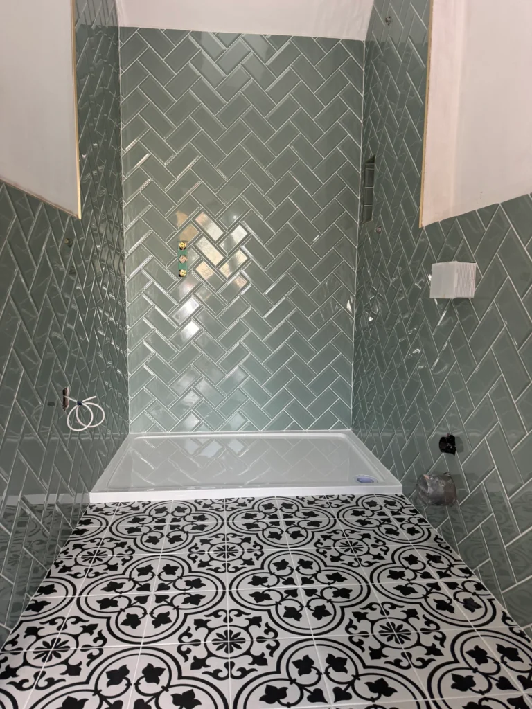 Green herringbone bathroom wall tiles with patterned floor tiles installed by Stamford tiler covering Stamford, Oakham and Uppingham.